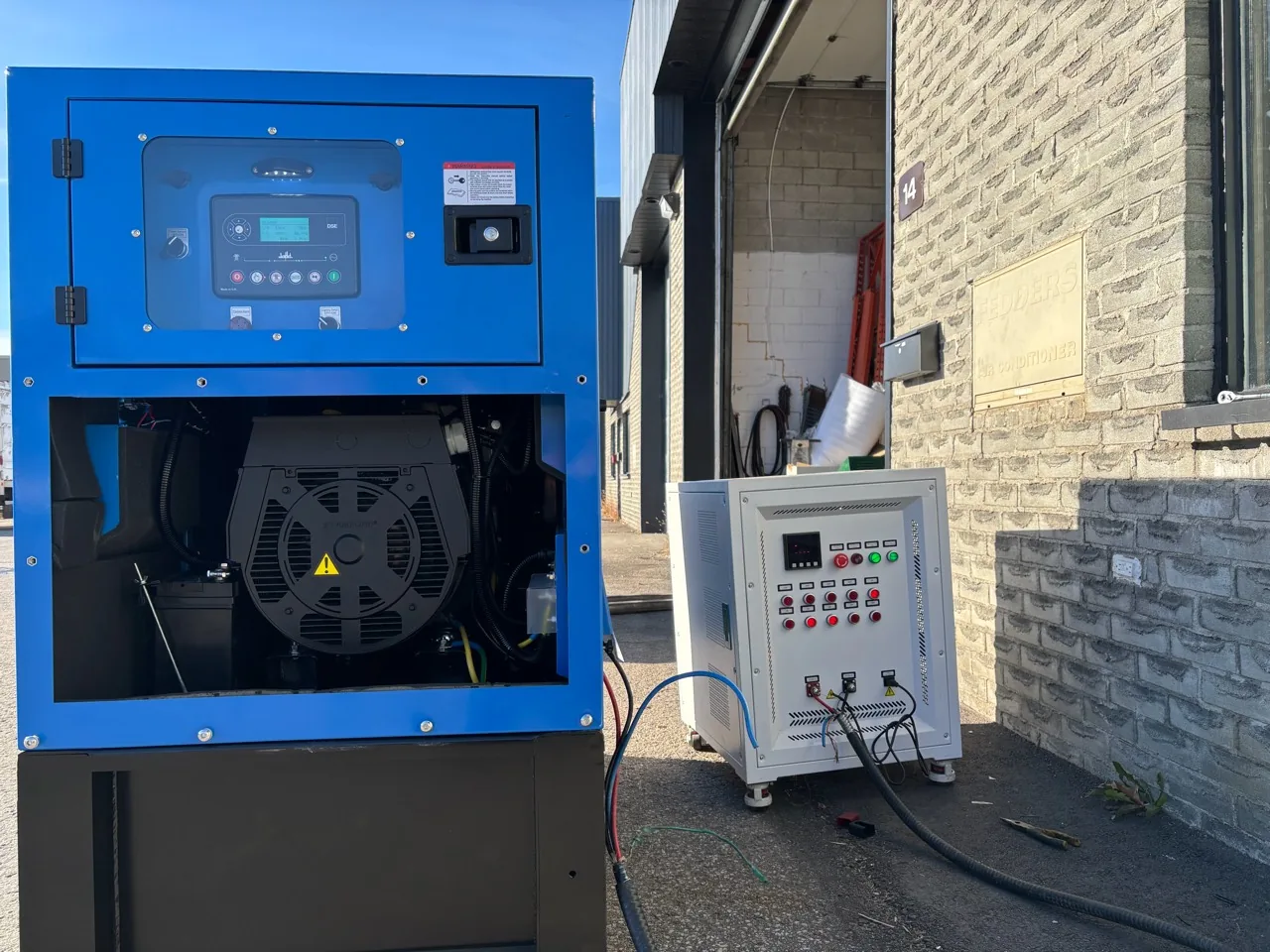 Génératrice bleue avec coffret électrique séparé devant le local